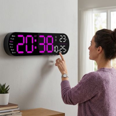 Femme en pull mauve manipule horloge digitale murale multifonction sur mur blanc