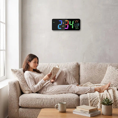 Femme lisant dans canapé avec horloge digitale murale affichant heure température et humidité