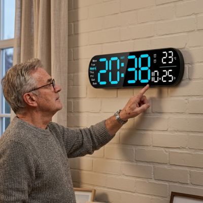 Homme consulte météo sur horloge digitale murale multifonction sur mur en brique