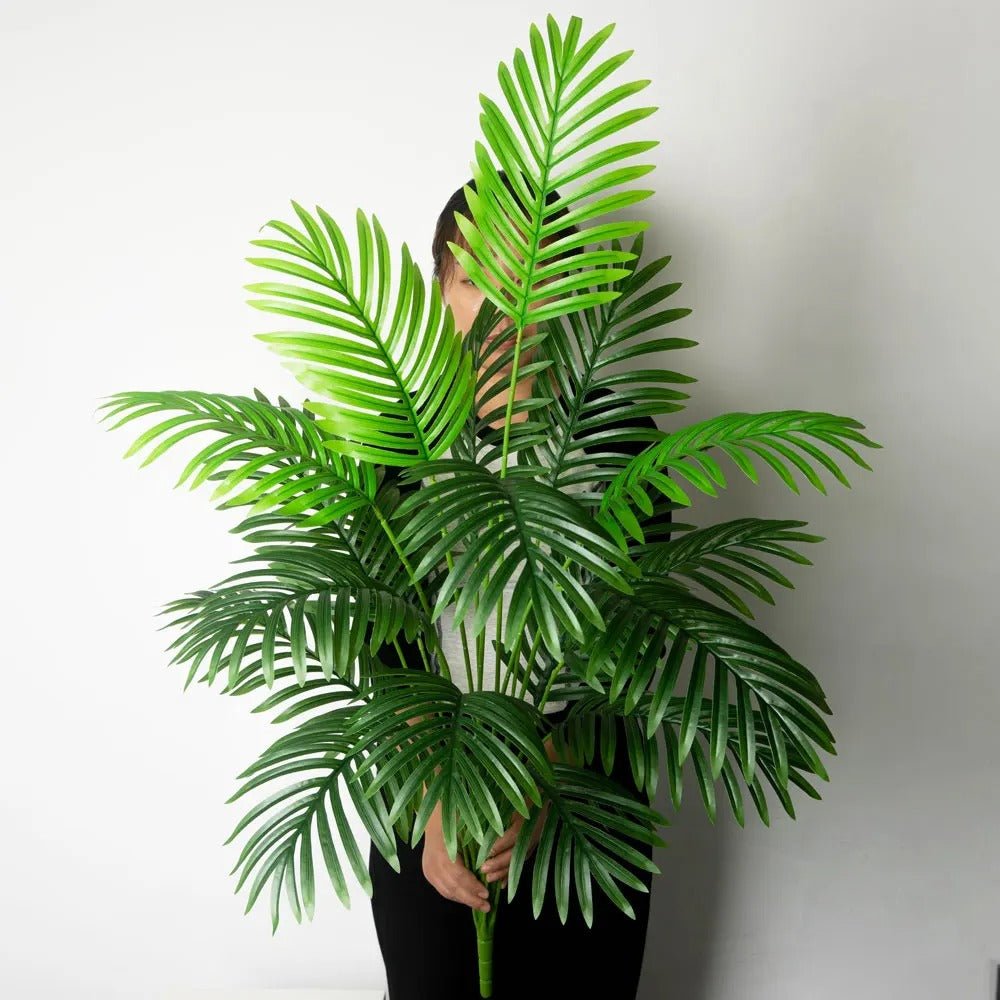 Dame tient une tige de grand Palmier Artificiel tropicana 120cm de 24 ffeuilles