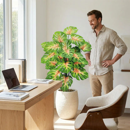 Homme admirant fièrementplante artificielle monstera dans bureau à domicile